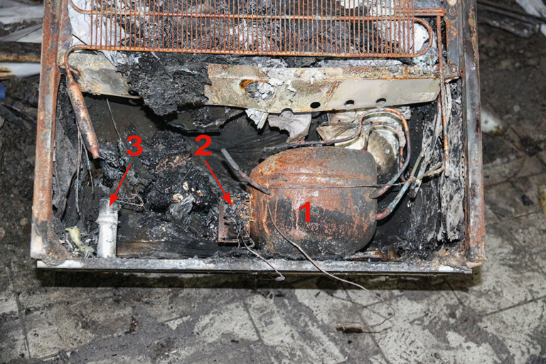 Bild 7 / Blick auf den Bereich mit dem Kompressor (1), dem Anlaufrelais (2) und dem Kondensator (3): Hier werden die intensivsten Brandschäden an dem Gerät festgestellt. Die Bauteile weisen zunächst jedoch keine Auffälligkeiten auf.