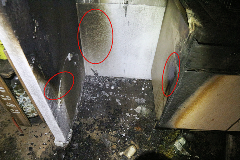 Bild 9 / Blick auf den Brandausbruchbereich im ehemaligen Aufstellbereich der Kühlgefrierkombination: Die tiefsten Brandschäden beginnen etwas über dem Bodenniveau (rote Markierungen).