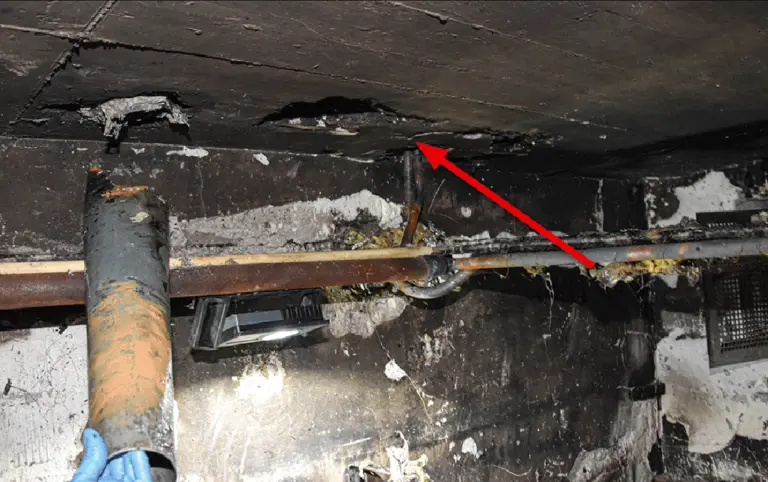 Bild 2 / In der Decke des Brandraumes im Keller befinden sich die Öffnung für die Ascheentsorgung und daneben eine Lüftungsöffnung (Pfeil).