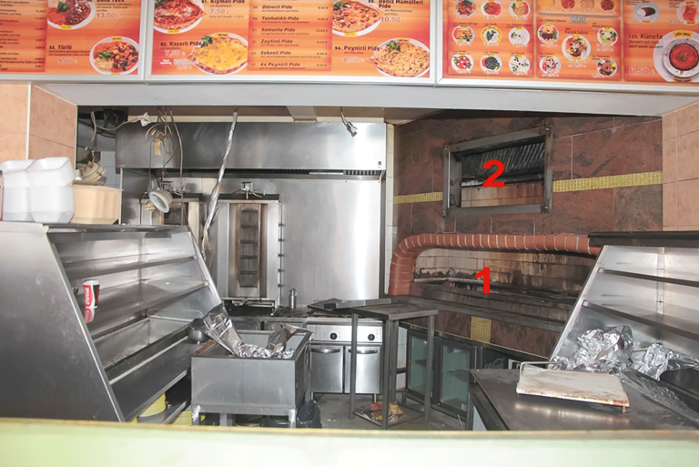 Bild 1 / Blick in die offene Küche mit dem Holzkohlegrill (1) und der Dunstabzugshaube (2)